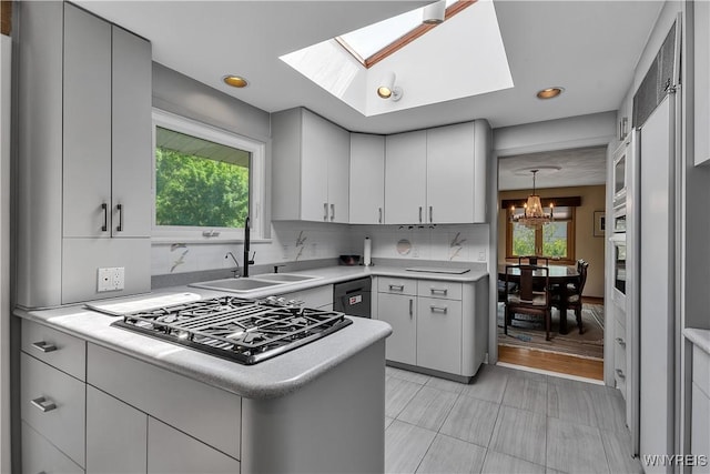 9325 Hunting Valley Rd N, Clarence, NY 14031 - kitchen with gas stovetop, light countertops, a skylight, decorative backsplash, and healthy amount of natural light