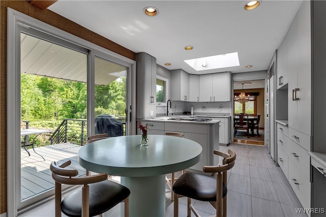 9325 Hunting Valley Rd N, Clarence, NY 14031 - kitchen with a chandelier, a skylight, light tile patterned flooring, recessed lighting, and light countertops