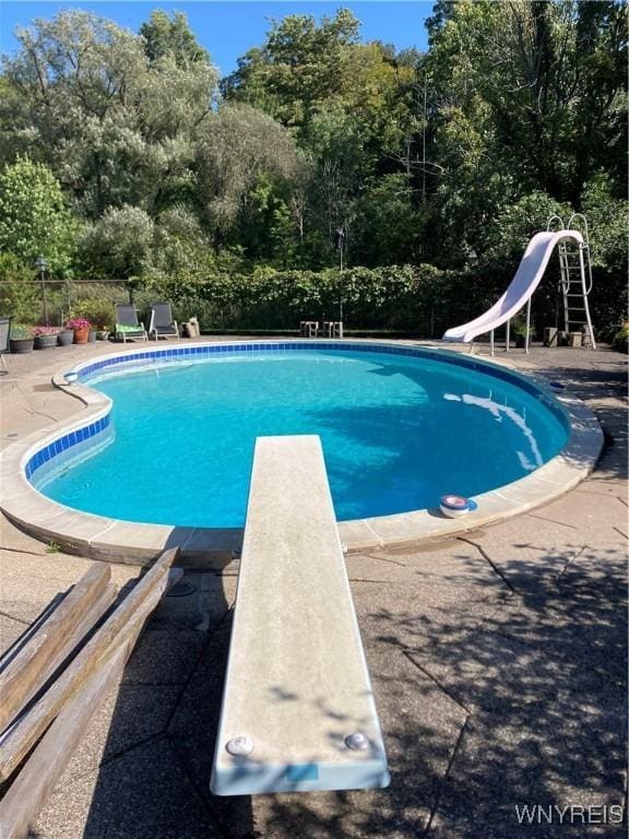 9325 Hunting Valley Rd N, Clarence, NY 14031 - view of swimming pool with a diving board, a water slide, a patio, and view of wooded area