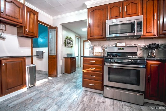 2019 Center St, North Collins, NY 14111 - kitchen featuring appliances with stainless steel finishes, ornamental molding, dark countertops, light wood-style flooring, and backsplash
