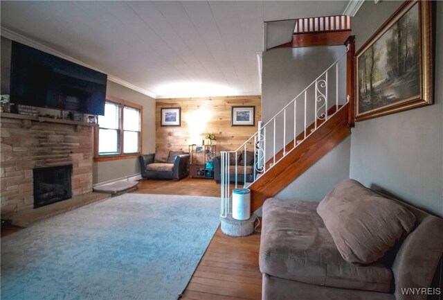 2019 Center St, North Collins, NY 14111 - living room featuring wood finished floors, stairs, crown molding, wooden walls, and a fireplace