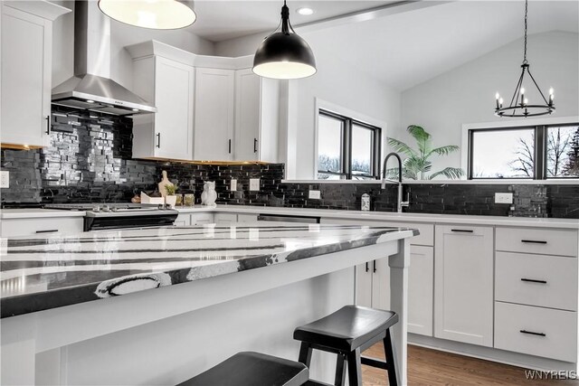 4 Streamsong Ct, Amherst, NY 14051 - kitchen with wall chimney range hood, healthy amount of natural light, decorative backsplash, a kitchen breakfast bar, and vaulted ceiling