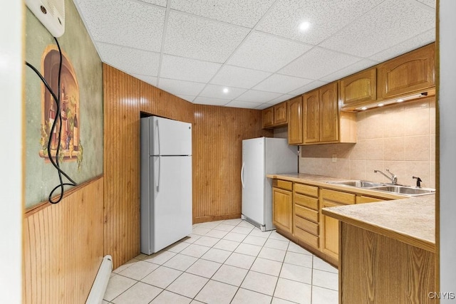 2260 Lamson Rd, Lysander, NY 13135 - kitchen featuring freestanding refrigerator, a sink, wood walls, light countertops, and light tile patterned floors