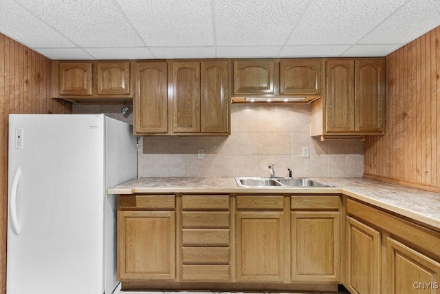 2260 Lamson Rd, Lysander, NY 13135 - kitchen featuring a sink, freestanding refrigerator, light countertops, a paneled ceiling, and wood walls