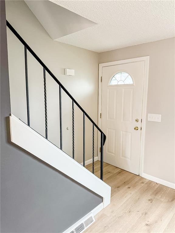 90 Fox Run, Gates, NY 14606 - foyer featuring light wood-style flooring, baseboards, stairway, and a textured ceiling