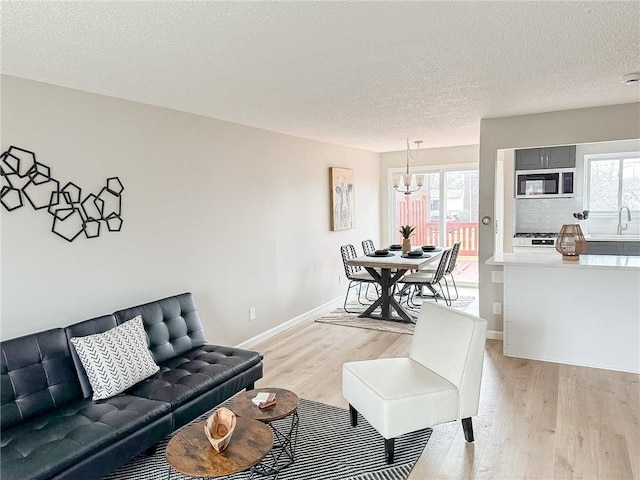 90 Fox Run, Gates, NY 14606 - living area featuring light wood finished floors, a textured ceiling, baseboards, and a chandelier