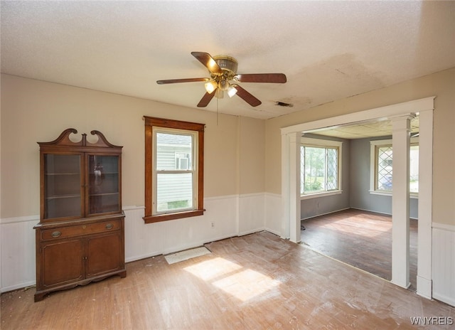 2215 S Ave, Niagara Falls, NY 14305 - empty room with light wood-style floors, wainscoting, ceiling fan, and ornate columns