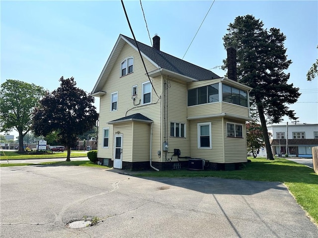 1845 N Clinton Ave, Rochester, NY 14621 - view of side of home with a chimney, central AC unit, and a lawn