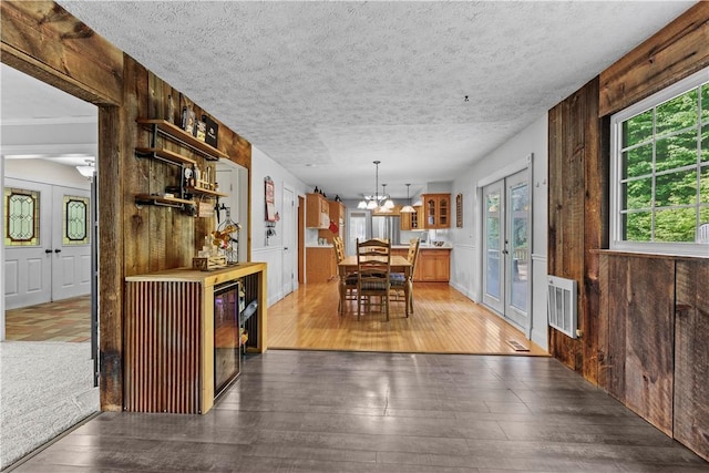 7425 State Route 20a, Bristol, NY 14469 - dining space with hardwood / wood-style flooring, wood walls, a chandelier, and a textured ceiling
