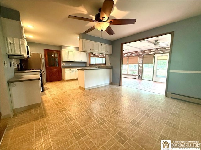 56 Otter St, Dunkirk-City, NY 14048 - kitchen with dark countertops, ceiling fan, white cabinets, a baseboard heating unit, and a peninsula