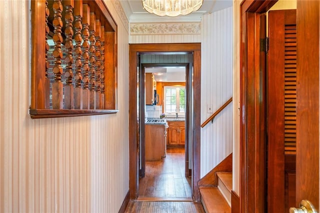 377 Winfield Rd, Irondequoit, NY 14622 - hall featuring wood-type flooring, ornamental molding, wallpapered walls, stairs, and a chandelier