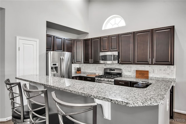 27 Skylark Ln, Wheatfield, NY 14304 - kitchen with appliances with stainless steel finishes, backsplash, baseboards, a breakfast bar, and a high ceiling