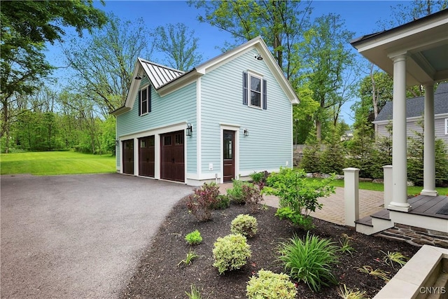 149 E Genesee St, Skaneateles, NY 13152 - view of side of home with an attached garage, a standing seam roof, driveway, metal roof, and a yard