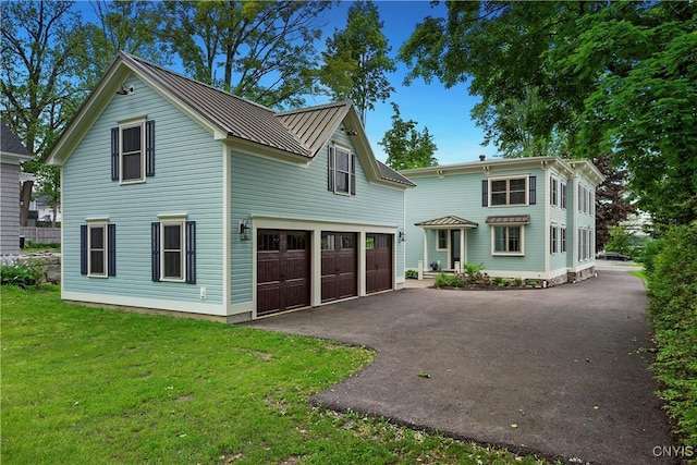 149 E Genesee St, Skaneateles, NY 13152 - view of front of house featuring driveway, a front lawn, metal roof, and a garage
