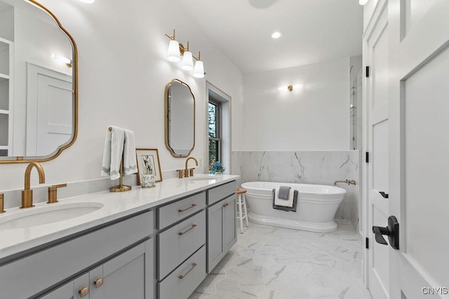 149 E Genesee St, Skaneateles, NY 13152 - bathroom featuring marble finish flooring, double vanity, a soaking tub, a wainscoted wall, and recessed lighting