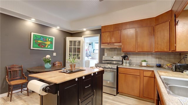 51 Sherrill St Unit 1, Geneva-City, NY 14456 - kitchen featuring gas range, under cabinet range hood, decorative backsplash, light wood-type flooring, and brown cabinetry