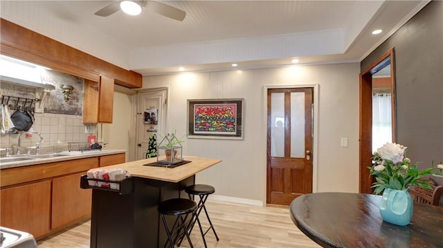 51 Sherrill St Unit 1, Geneva-City, NY 14456 - kitchen featuring a sink, light wood-type flooring, tasteful backsplash, a kitchen island, and ceiling fan