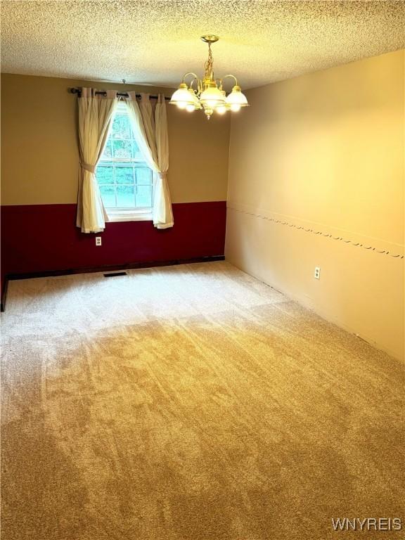 897 Fairmont Ave, North Tonawanda, NY 14120 - unfurnished room featuring a chandelier, carpet flooring, and a textured ceiling