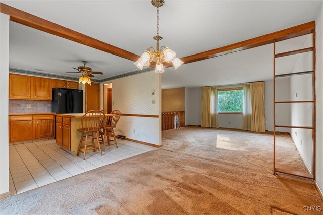 112 Elmcrest Cir, Salina, NY 13090 - kitchen with freestanding refrigerator, light carpet, a ceiling fan, a breakfast bar, and brown cabinetry