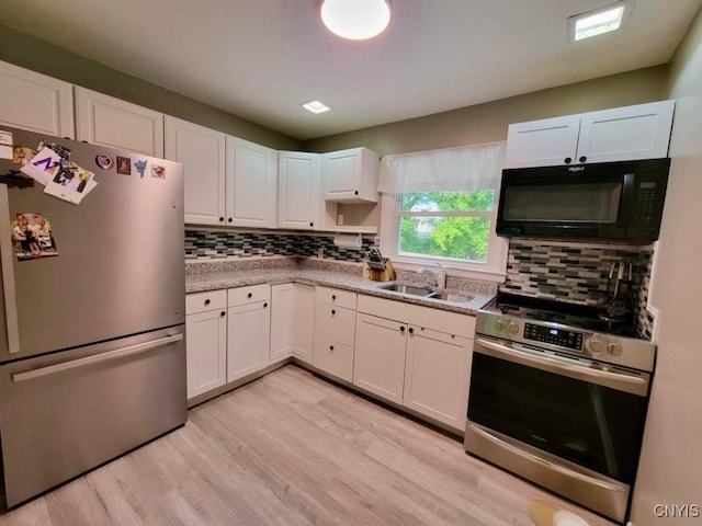 706 Dawes Ave, Utica, NY 13502 - kitchen featuring appliances with stainless steel finishes, a sink, light wood finished floors, white cabinetry, and decorative backsplash