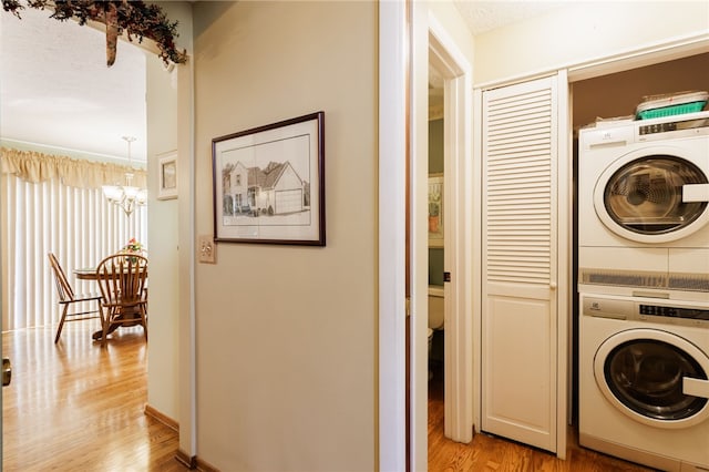 281 Burley Rd, Rochester, NY 14612 - laundry area with stacked washer / dryer, a chandelier, and light wood-style floors