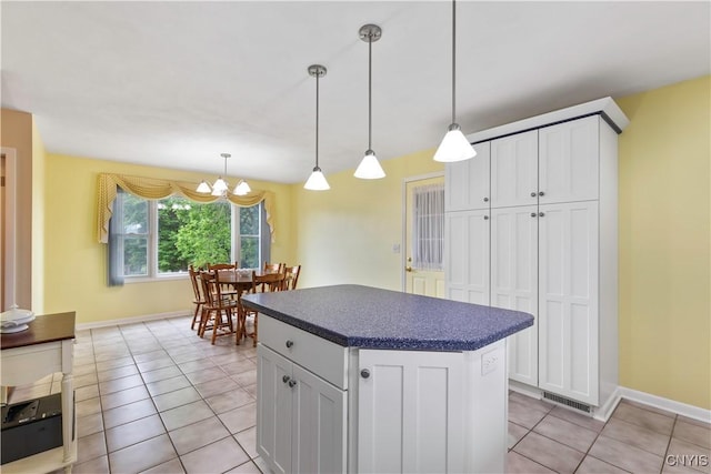 2220 W Genesee Tpke, Camillus, NY 13031 - kitchen featuring dark countertops, light tile patterned floors, a kitchen island, white cabinets, and a chandelier