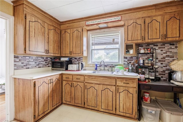 12 Queensboro Rd, Irondequoit, NY 14609 - kitchen with a sink, brown cabinets, light countertops, tasteful backsplash, and light flooring
