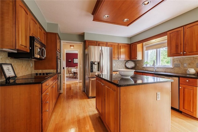 74 Broadmoor Trl, Perinton, NY 14450 - kitchen featuring stainless steel appliances, a sink, light wood-style flooring, a center island, and dark stone countertops