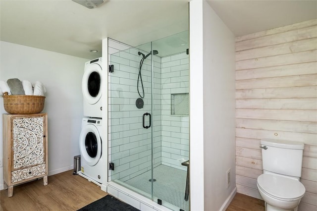 2309 Mcburney Rd, Phelps, NY 14432 - full bathroom with stacked washer and clothes dryer, wood finished floors, a shower stall, toilet, and baseboards