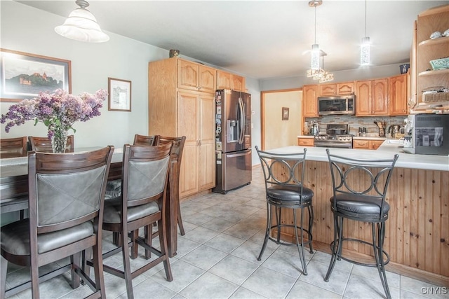 1 Carol Dr, Adams, NY 13605 - kitchen with appliances with stainless steel finishes, decorative backsplash, a peninsula, light tile patterned flooring, and a kitchen breakfast bar