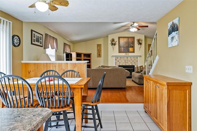 75 Red Rock Cir, Greece, NY 14626 - dining room featuring a ceiling fan, lofted ceiling, and a tile fireplace