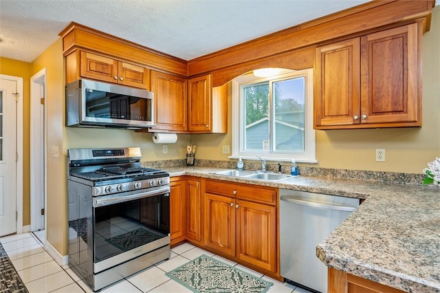 75 Red Rock Cir, Greece, NY 14626 - kitchen featuring appliances with stainless steel finishes, brown cabinetry, a sink, light tile patterned floors, and light countertops