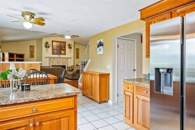 75 Red Rock Cir, Greece, NY 14626 - kitchen with stainless steel fridge with ice dispenser, a ceiling fan, a tiled fireplace, vaulted ceiling, and light tile patterned flooring