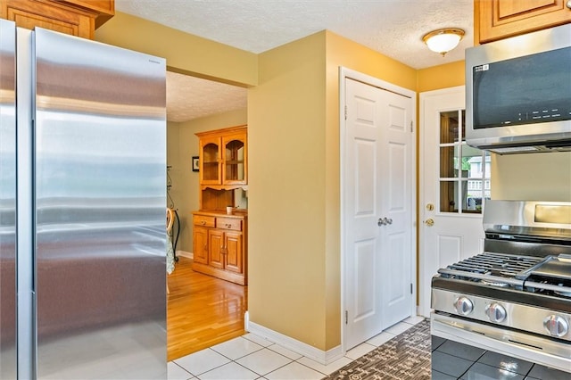 75 Red Rock Cir, Greece, NY 14626 - kitchen featuring stainless steel appliances, a textured ceiling, light tile patterned flooring, and baseboards