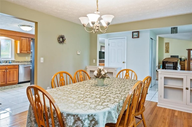 75 Red Rock Cir, Greece, NY 14626 - dining space with a chandelier, light wood-type flooring, and a textured ceiling