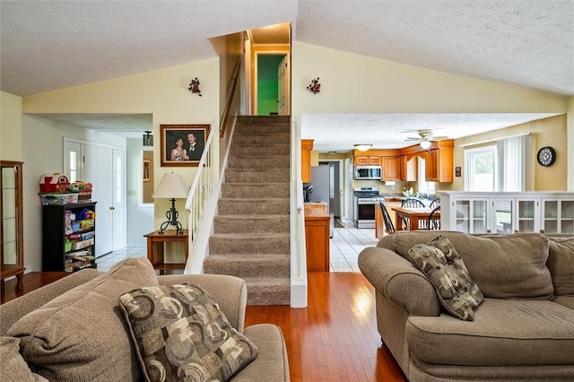 75 Red Rock Cir, Greece, NY 14626 - living area with vaulted ceiling, stairs, a textured ceiling, light wood finished floors, and ceiling fan