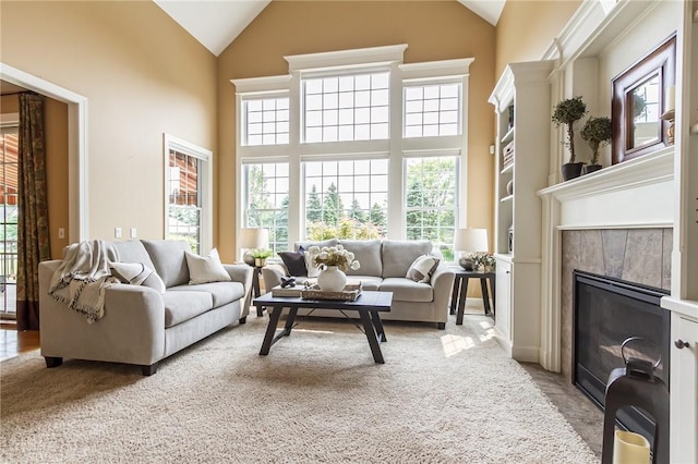 6305 Candlelight Run, Victor, NY 14564 - living room featuring healthy amount of natural light, high vaulted ceiling, a tiled fireplace, and light colored carpet