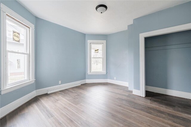 286 Kenwood Ave, Rochester, NY 14611 - unfurnished bedroom with multiple windows, dark wood-style floors, and baseboard heating