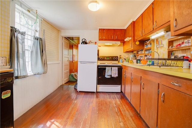 59 Elm St, Otsego, NY 13326 - kitchen with range with electric stovetop, freestanding refrigerator, wood-type flooring, under cabinet range hood, and brown cabinetry