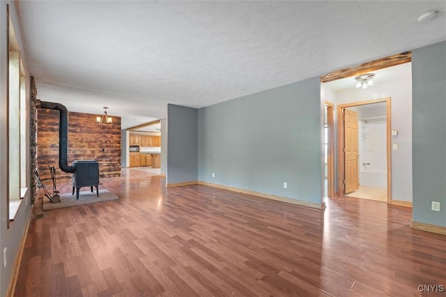 6669 Rottamore Rd, Stockbridge, NY 13409 - unfurnished living room featuring a wood stove, wood finished floors, a textured ceiling, baseboards, and wood walls