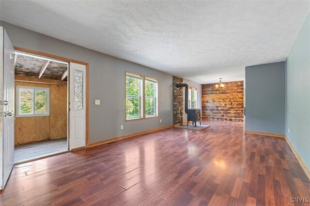 6669 Rottamore Rd, Stockbridge, NY 13409 - unfurnished living room featuring a wood stove, wood finished floors, a textured ceiling, plenty of natural light, and wood walls