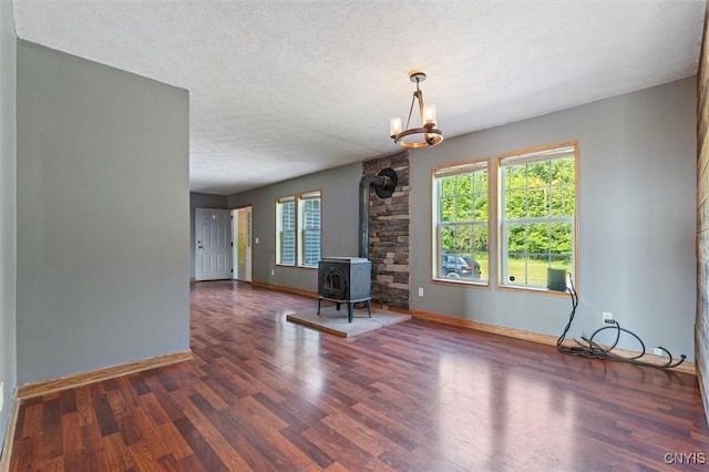 6669 Rottamore Rd, Stockbridge, NY 13409 - unfurnished living room featuring a wood stove, a textured ceiling, wood finished floors, and baseboards