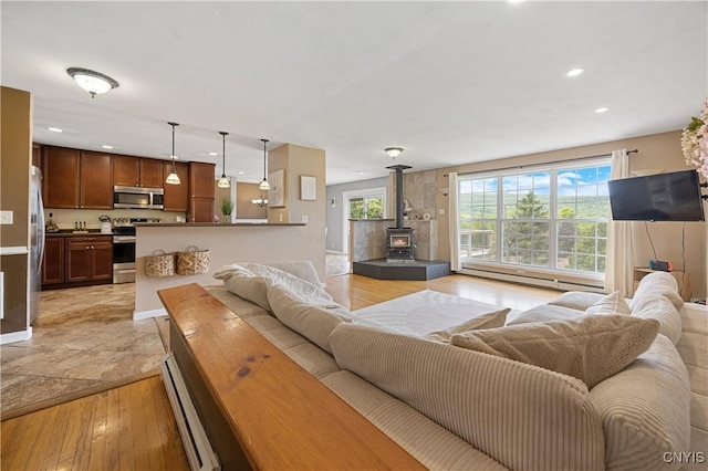 3477 Mcclary Rd, Lafayette, NY 13084 - living area with a wood stove, a baseboard heating unit, recessed lighting, light wood-style floors, and baseboards