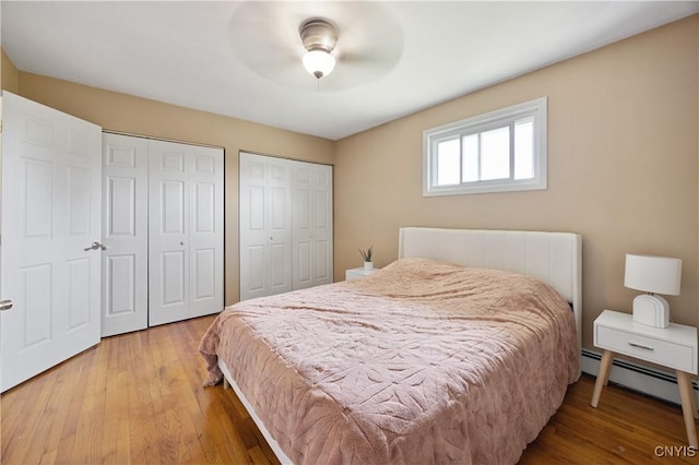 3477 Mcclary Rd, Lafayette, NY 13084 - bedroom featuring two closets, wood finished floors, baseboard heating, and ceiling fan