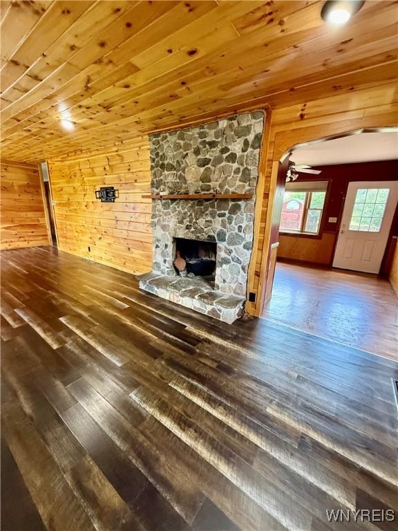 3394 Pike Rd, Alexander, NY 14020 - unfurnished living room featuring wooden walls, hardwood / wood-style floors, a fireplace, wooden ceiling, and a ceiling fan