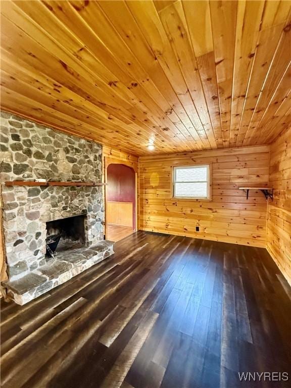 3394 Pike Rd, Alexander, NY 14020 - unfurnished living room with wooden ceiling, arched walkways, dark wood-style flooring, wood walls, and a fireplace