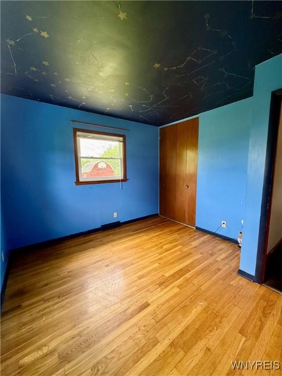 3394 Pike Rd, Alexander, NY 14020 - unfurnished bedroom with wood finished floors, a closet, and baseboards