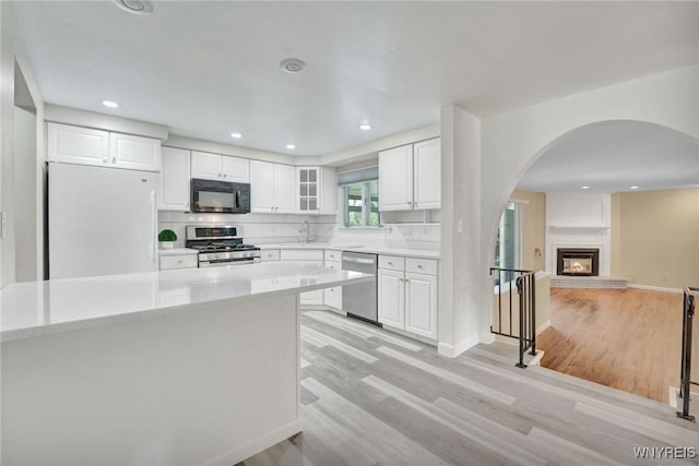 61 Caesar Blvd, Amherst, NY 14221 - kitchen featuring stainless steel appliances, arched walkways, light wood finished floors, white cabinetry, and recessed lighting