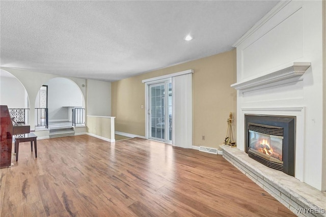 61 Caesar Blvd, Amherst, NY 14221 - unfurnished living room with wood finished floors, a fireplace, arched walkways, recessed lighting, and a textured ceiling