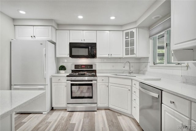 61 Caesar Blvd, Amherst, NY 14221 - kitchen featuring stainless steel appliances, white cabinets, a sink, light stone counters, and decorative backsplash